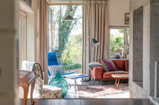 A living room located at The Garden House in Norton St philip with retro chairs and sofa and large glass windows